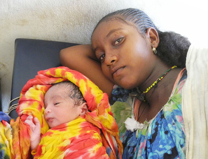 Eine junge Mutter mit ihrem Neugeborenen. Seine helle Haut wird sich erst in wenigen Tagen nach der Geburt dunkel färben.